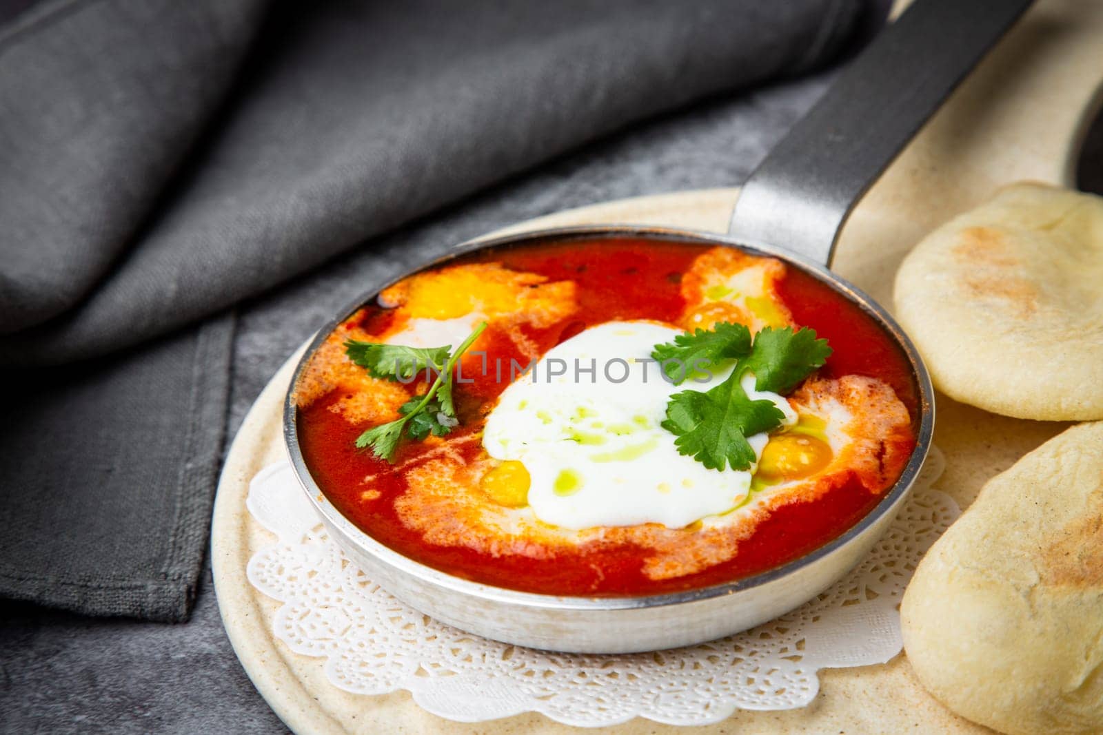 borscht in a frying pan with fresh flatbreads and cherry tomatoes