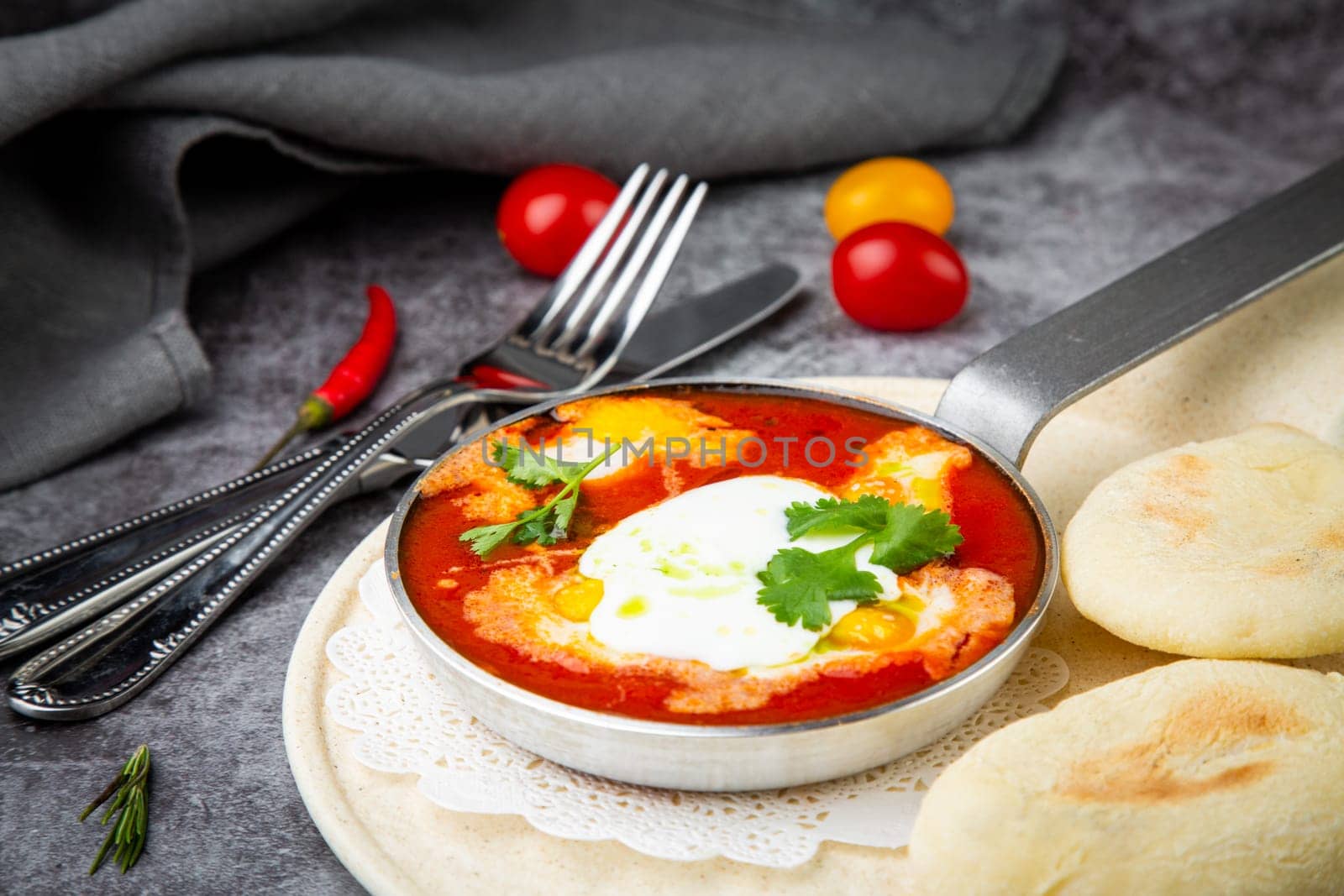 borscht in a frying pan with fresh flatbreads and cherry tomatoes side view by tewolf