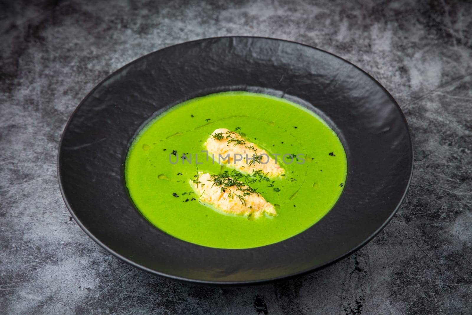 creamy broccoli soup with herbs in a black plate