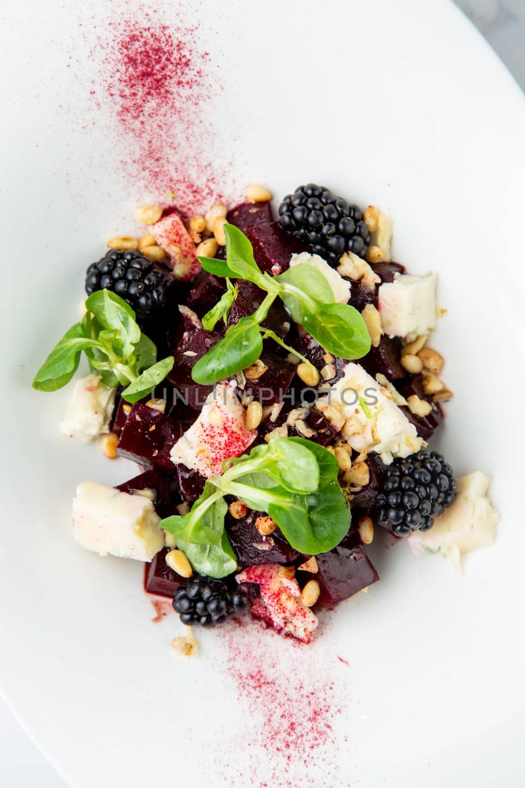 salad of blackberries, beets, seeds and cheese, side view on a white plate by tewolf