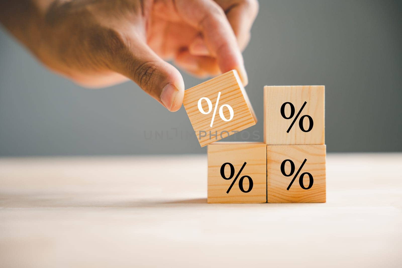 Businessman's hand arranging a wood cube block with a percentage symbol icon by Sorapop