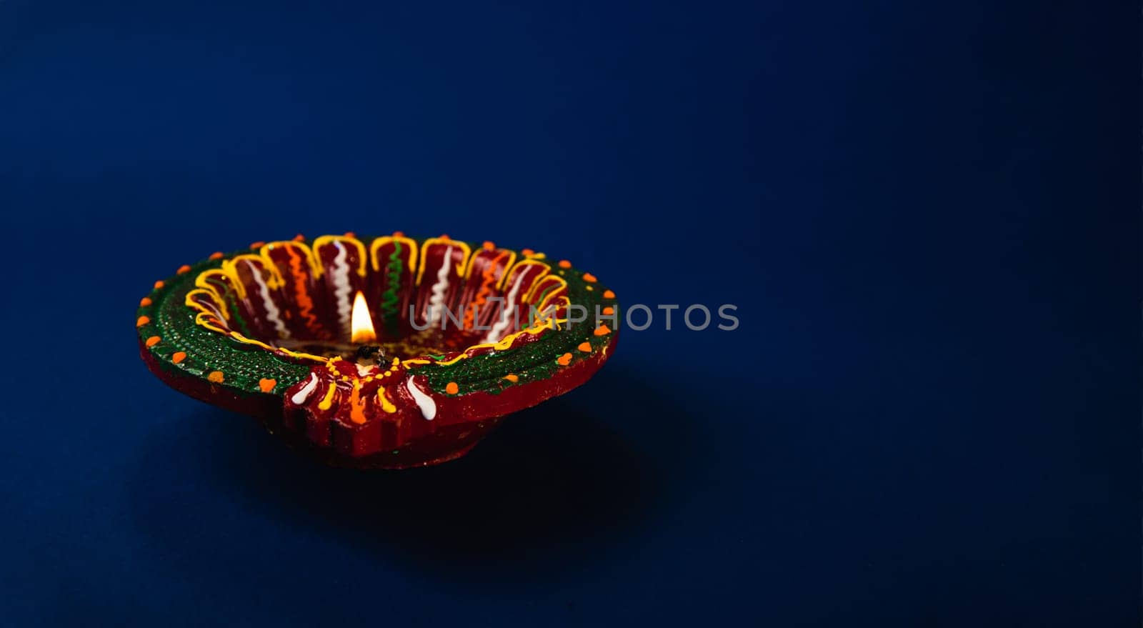 Celebrate Diwali with these radiant clay diya lamps, representing prosperity and happiness, illuminating the night against a blue background. Perfect for festive invitations, greeting cards by Sorapop