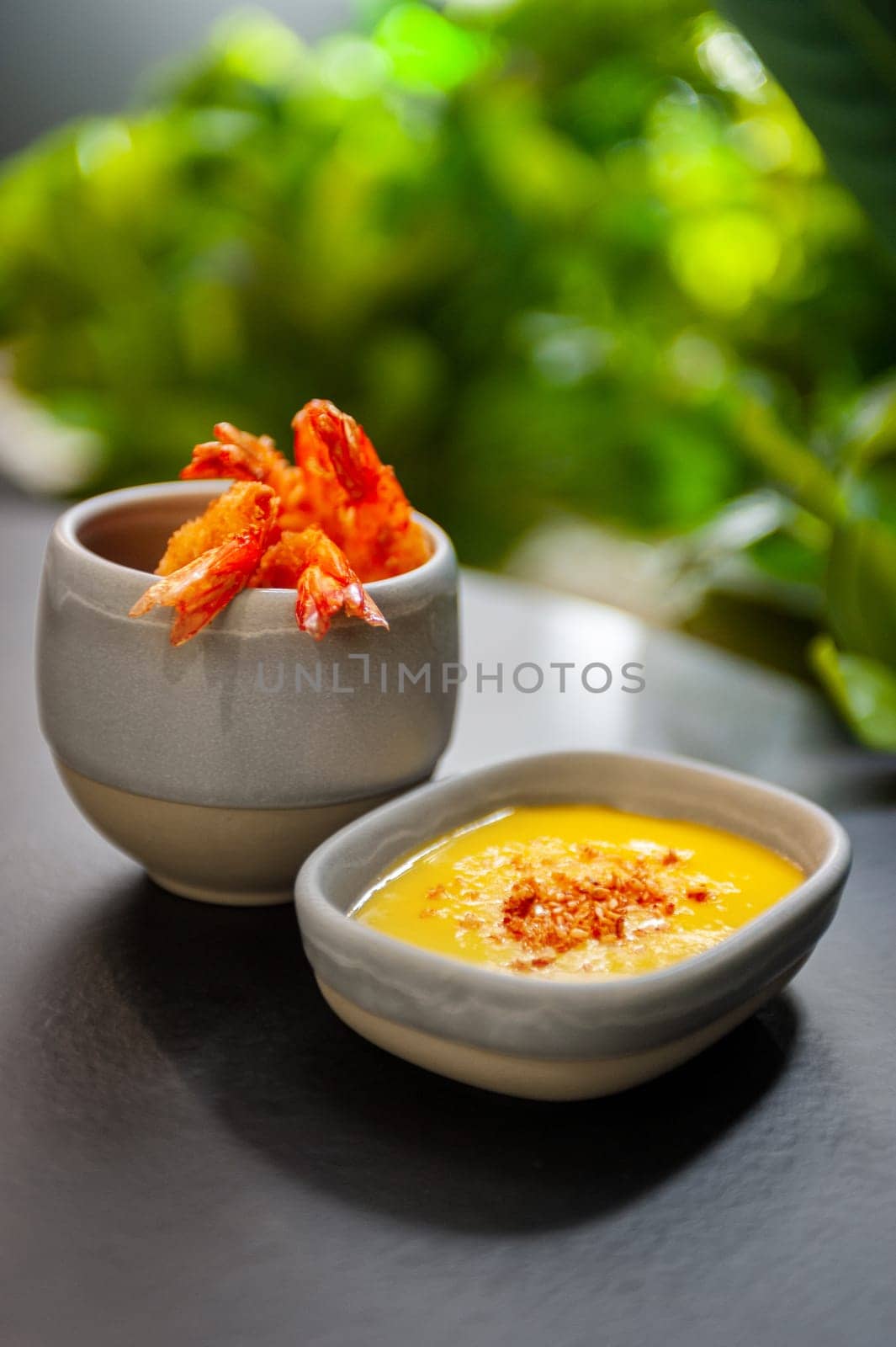 Tempura deep-fried shrimp with spiced sauce on a plate on a dark background. Appetizer in the style of Japanese cuisine. High quality photo.