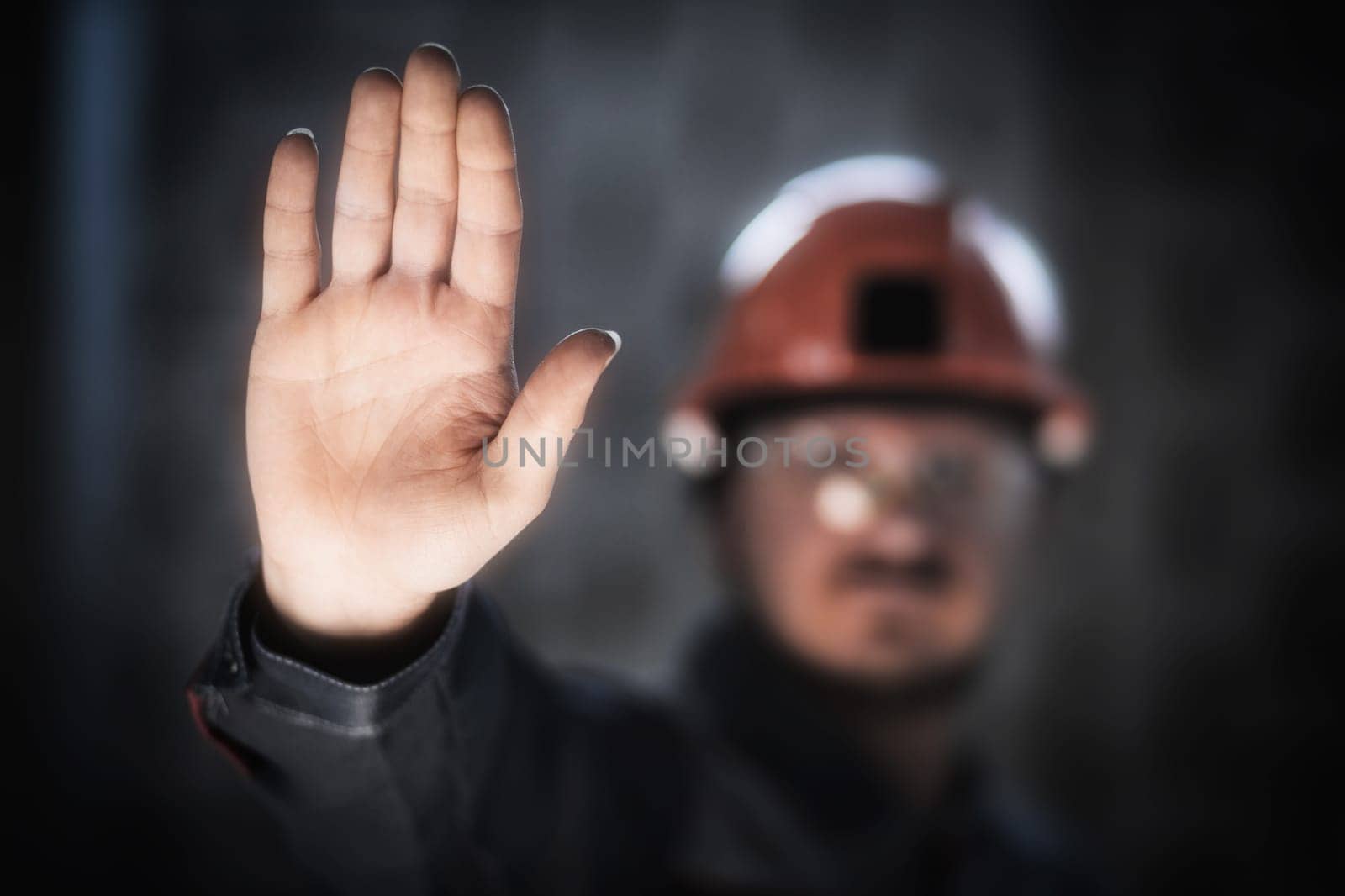 A miner or worker in overalls and a hard hat shows an open palm, a crisis in the workplace, a workers' strike by Rom4ek