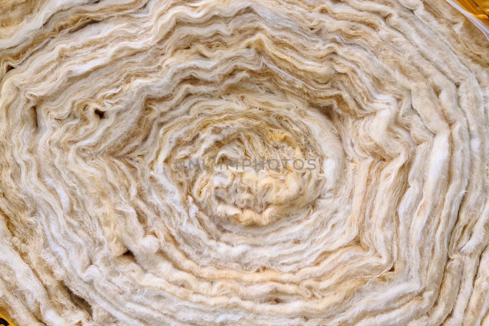 A roll of new twisted glass wool, a soft material for insulating walls and other structures, close-up, background.