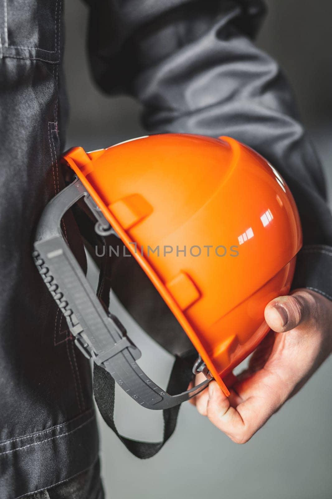 Safety helmet or hard hat is in the hands of a construction worker, vertical close up, construction site safety concept by Rom4ek