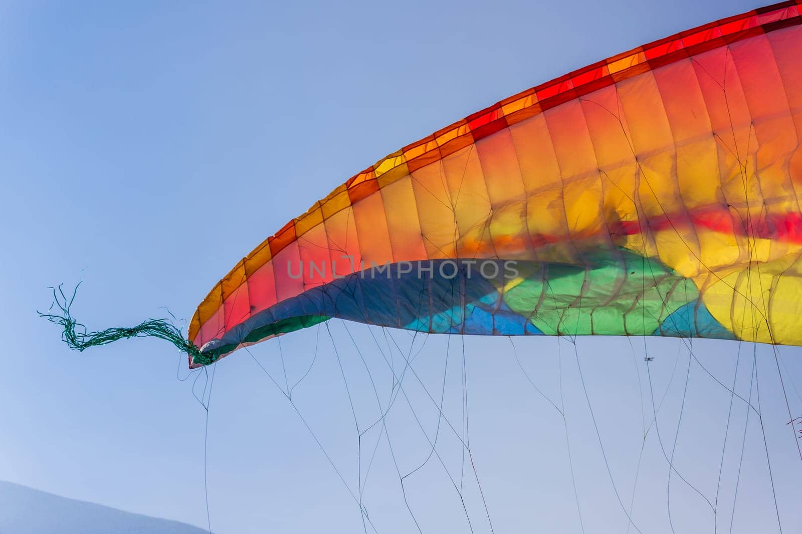 Close-up on part of the wing of a multi-colored paraglider against a blue sky by Rom4ek