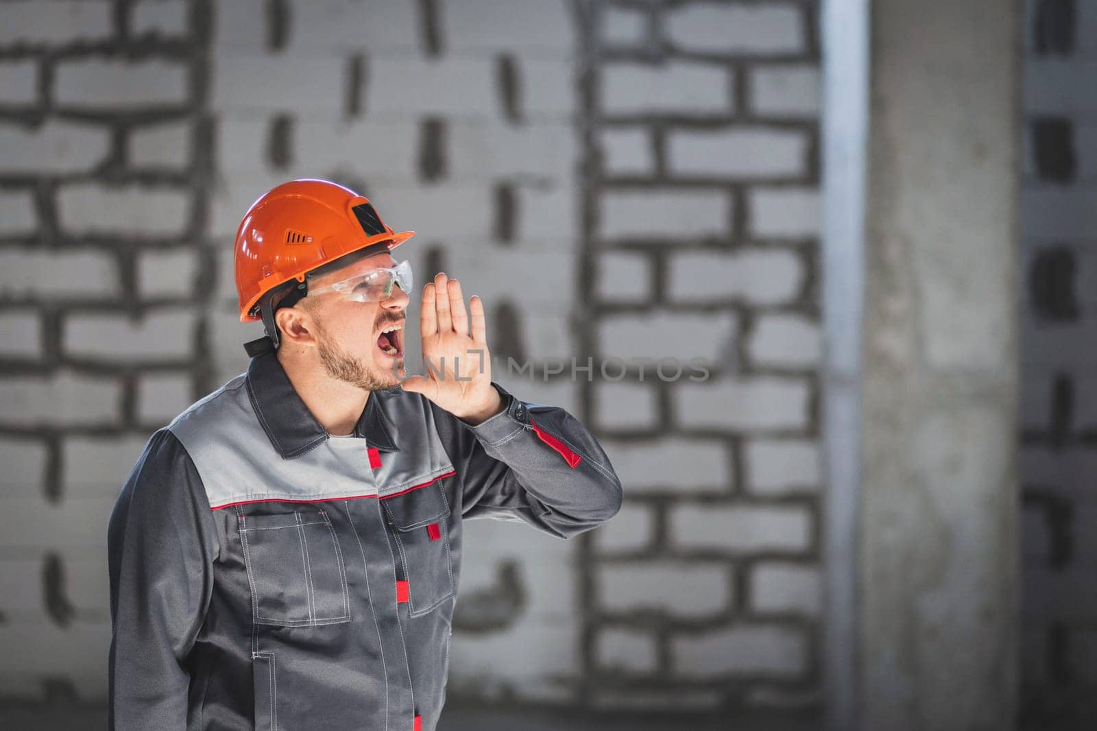 Portrait of a construction worker who shouts to other workers because of poor radio communication at a construction site by Rom4ek