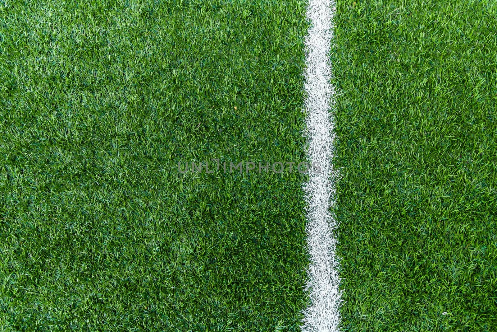 Vertical white stripe markings on the green grass of the football field by Rom4ek