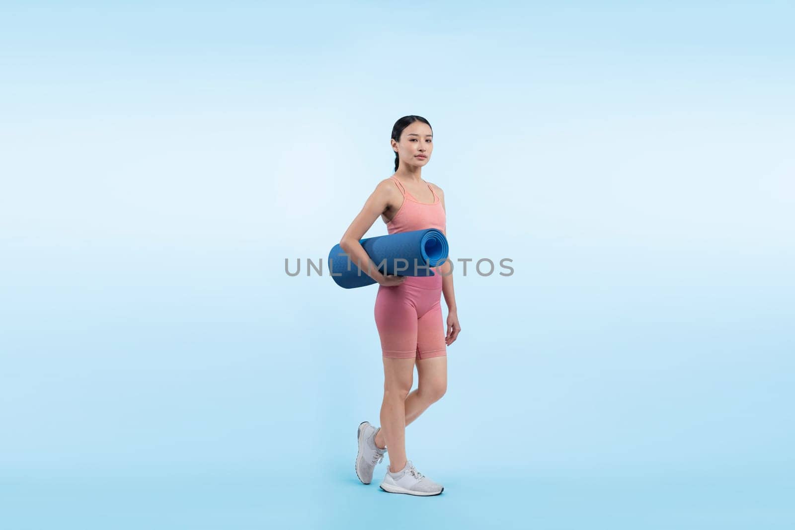 Young attractive asian woman portrait in sportswear with exercising mat. Healthy exercise and workout routine lifestyle concept. Studio shot isolated background. Vigorous