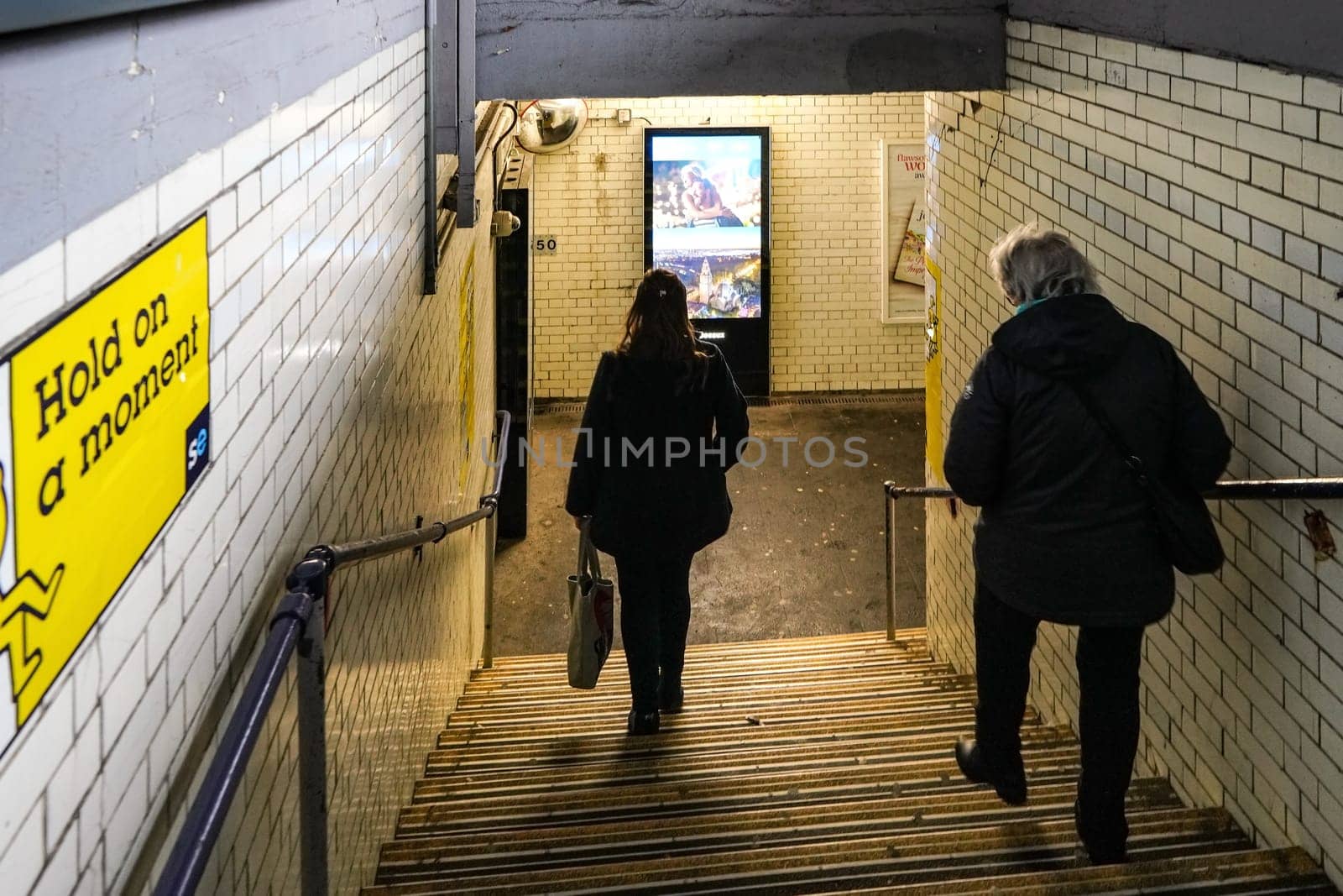 London, United Kingdom - February 01, 2019: Passengers walking down the stairs at pedestrian subway leading to other platform at Lewisham station.