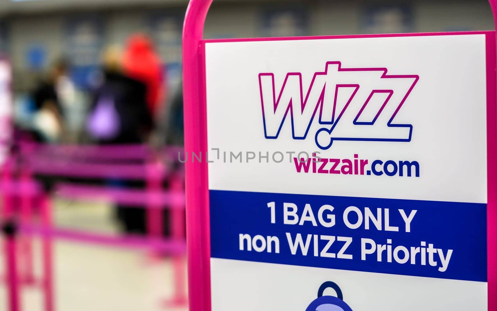 London, United Kingdom - February 05, 2019: Wizzair info table about maximum baggage size, blurred people at check in desks in background Wizz is Hungarian low cost operator founded in 2003 by Ivanko