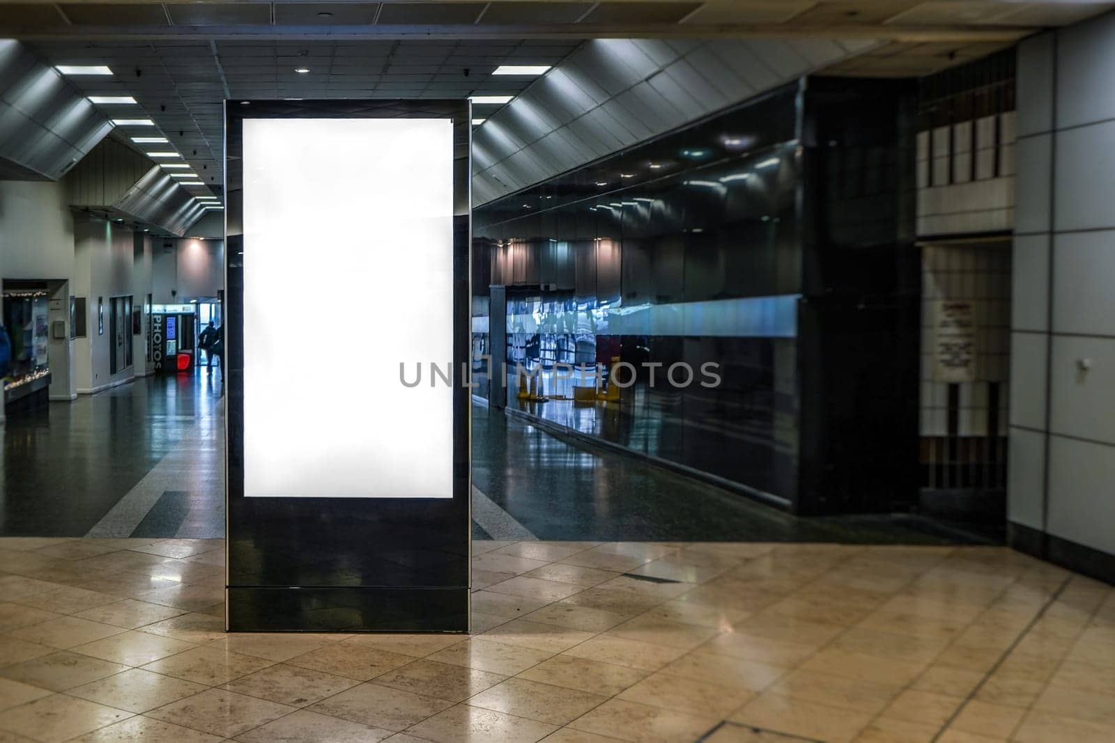 Ad screen mock up at small shopping centre, dark corridor leading outside in background