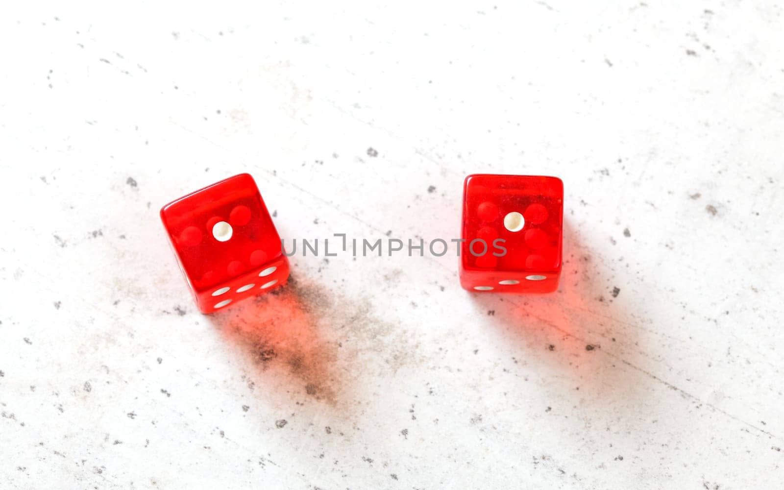 Two red craps dices showing Snake Eyes (double number one) overhead shot on white board