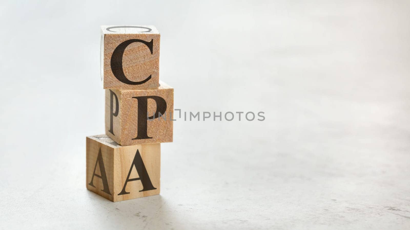 Pile with three wooden cubes - letters CPA meaning COST PER ACTION / ACQUISITION on them, space for more text / images at right side.