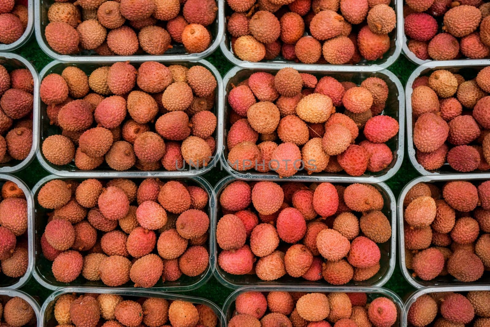 Overhead shot - lychee fruits in small plastic boxes, displayed on food market at Lewisham, London by Ivanko