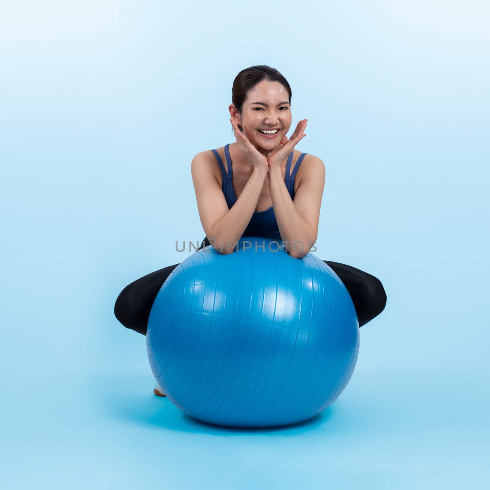 Young attractive asian woman portrait in sportswear with fit ball targeting on abs muscle for effective energetic daily workout routine. Studio shot and isolated background. Vigorous