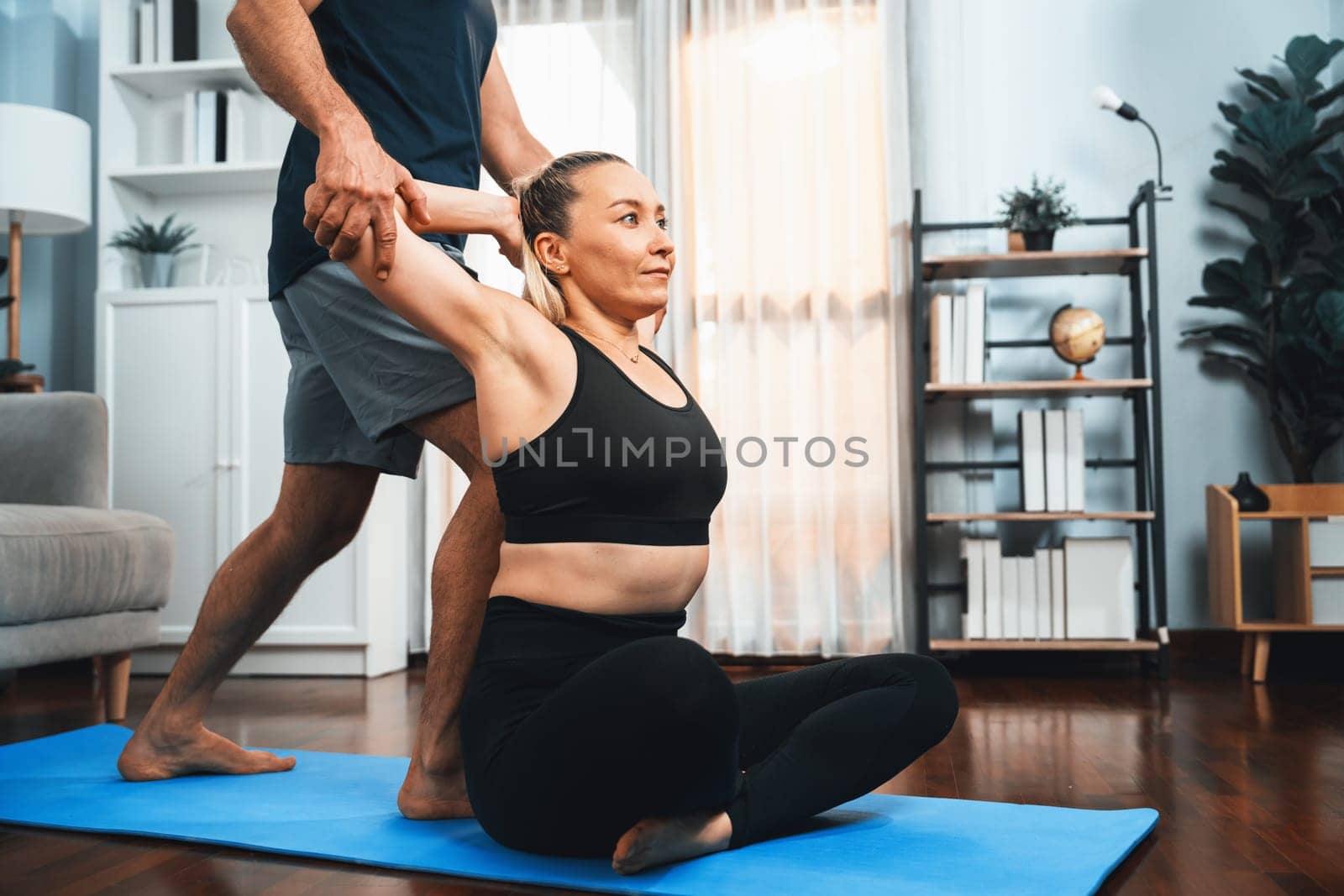 Happy active senior couple in sportswear being supportive and assist on yoga posture together at home. Healthy senior man and woman lifestyle with yoga exercise. Clout