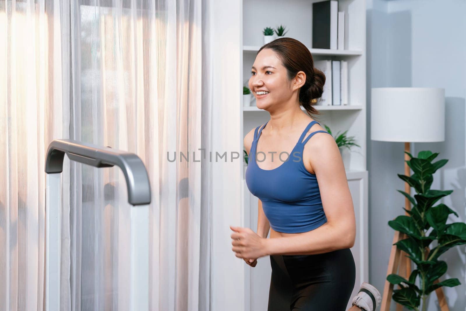 Energetic and strong athletic asian woman running running machine at home. Pursuit of fit physique and commitment to healthy lifestyle with home workout and training. Vigorous