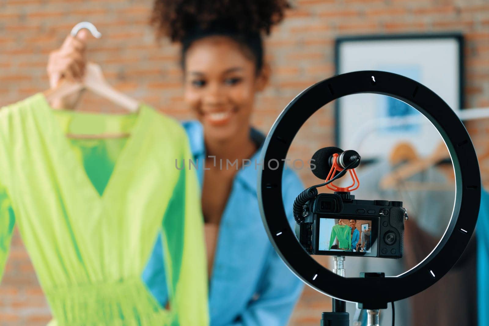 Woman influencer shoot live streaming vlog video review clothes crucial social media or blog. Happy young girl with apparel studio lighting for marketing recording session broadcasting online.