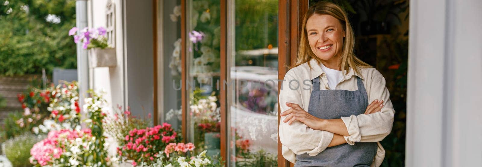 Woman florist small business owner standing with crossed arms near floral store. High quality photo