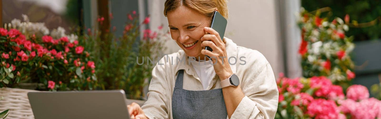 Smiling flower shop owner working on laptop computer. Occupation working concept