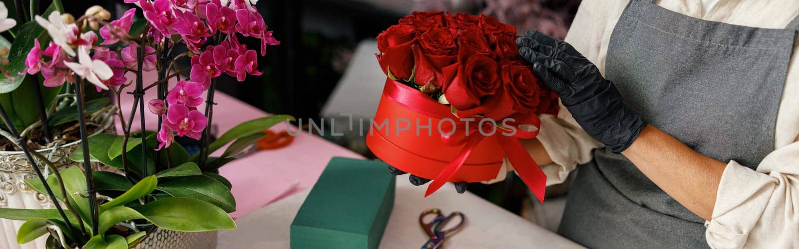 Woman florist flower shop owner hold roses composition on store background. High quality photo