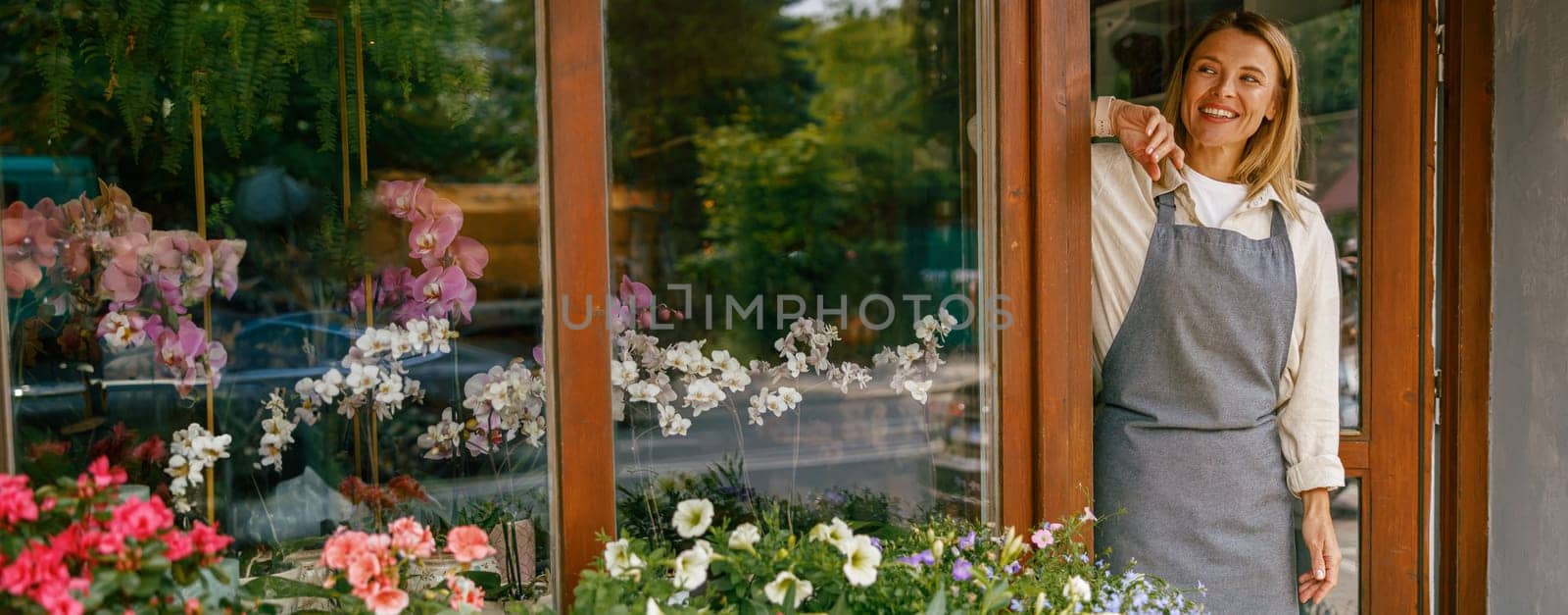 Smiling woman florist small business owner standing in own floral store and waiting for client by Yaroslav_astakhov