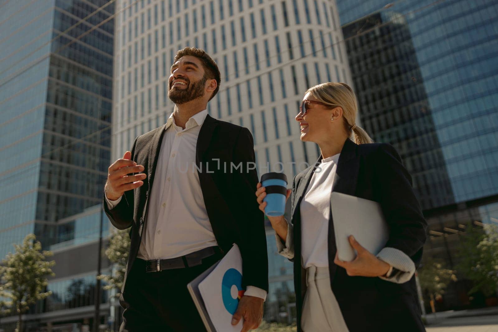 Business people talking during break time standing on background of modern city skyscrapers