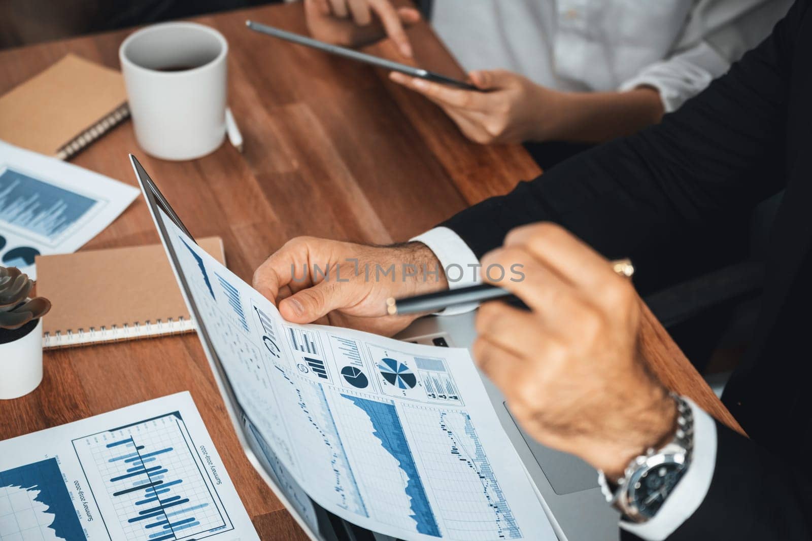 Diverse group of business analyst team analyzing financial data report paper on office table. Chart and graph dashboard by business intelligence analysis for strategic marketing planning Meticulous