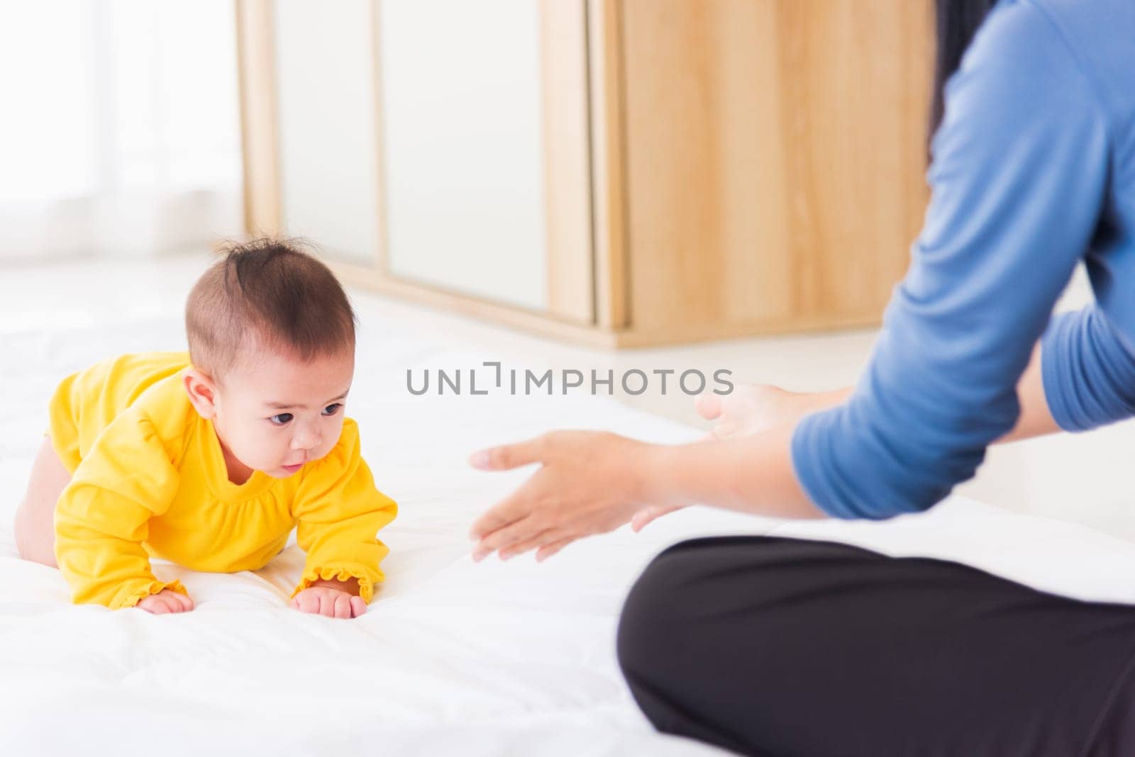 mother have fun learn walking crawling his daughter baby indoors bedroom by Sorapop