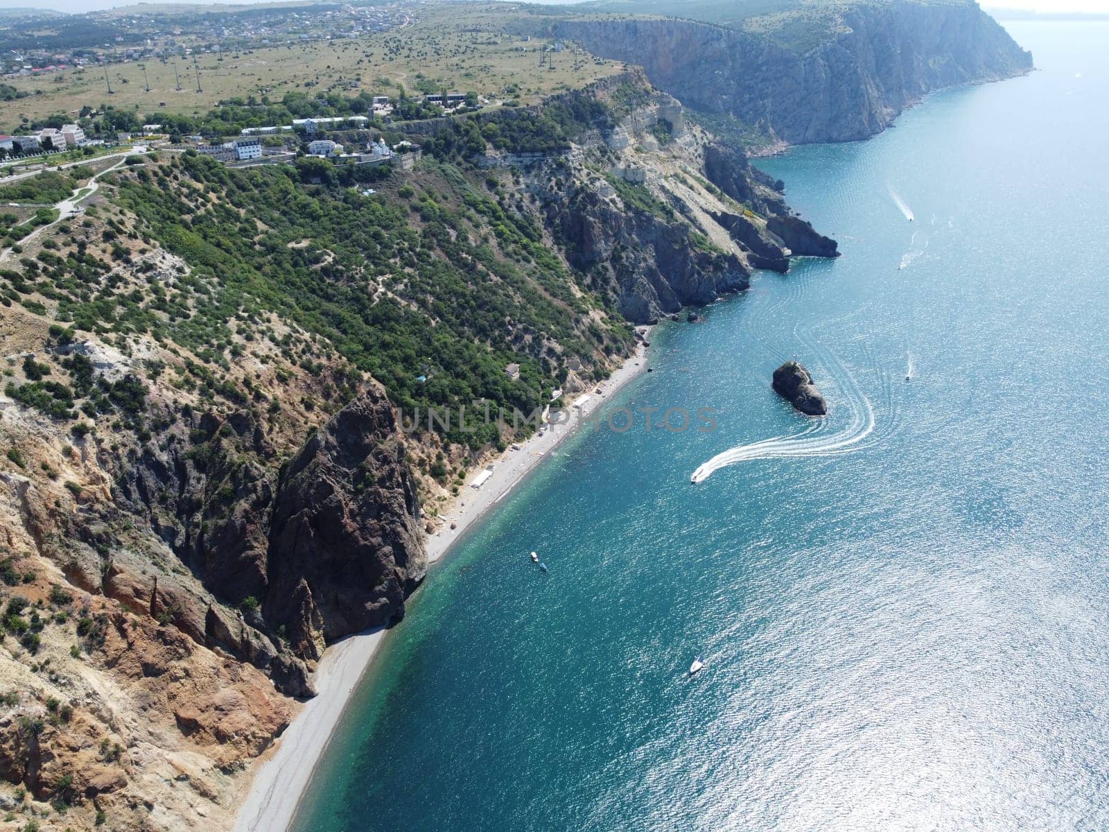 Aerial view from above on calm azure sea and volcanic rocky shores. Small waves on water surface in motion blur. Nature summer ocean sea beach background. Nobody. Holiday, vacation and travel concept by panophotograph