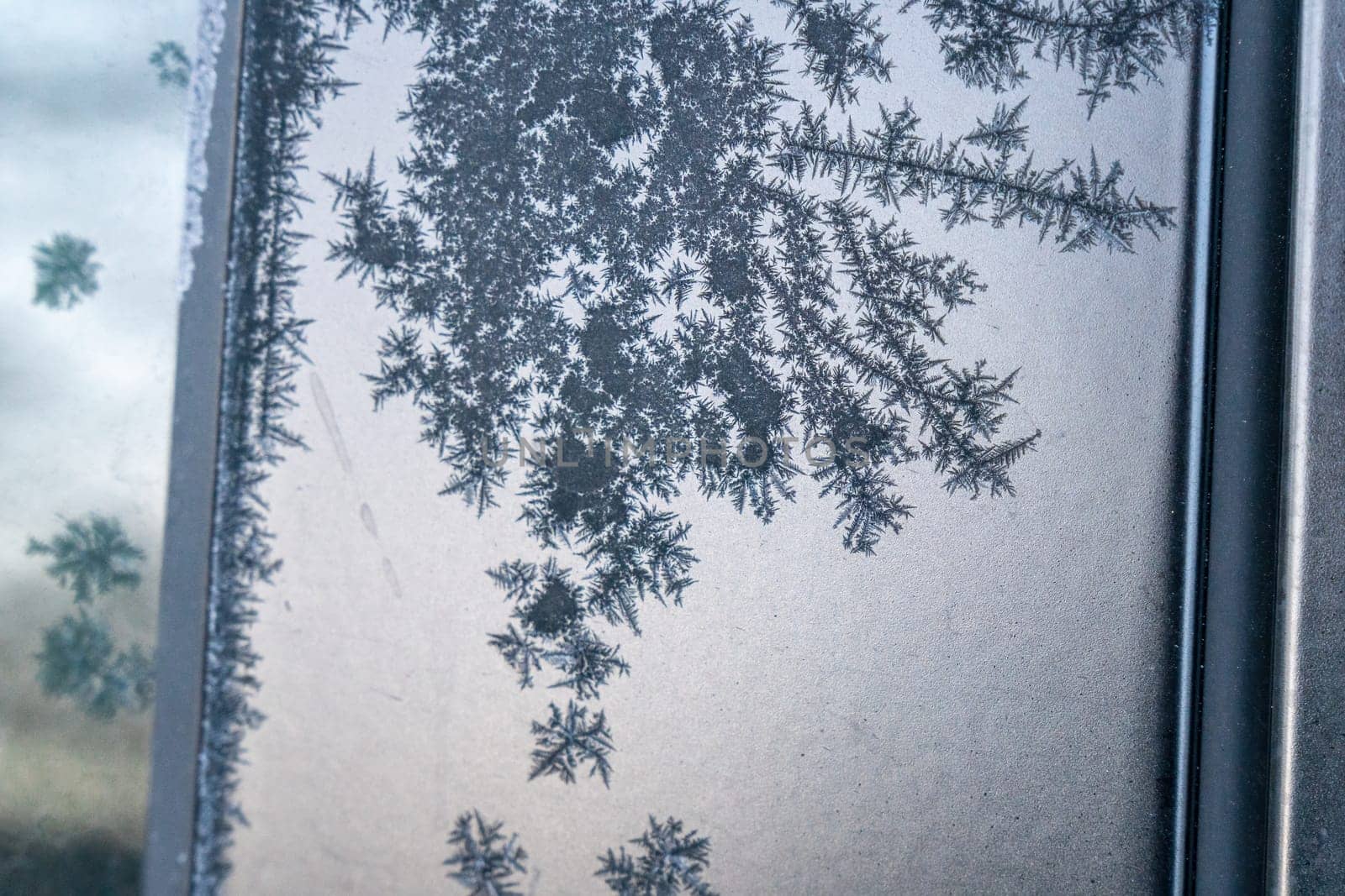Selective focus. First frost on a frozen black plastic, late autumn close-up. Beautiful abstract frozen microcosmos pattern. Freezing weather frost action in nature. Winter backdrop. by panophotograph