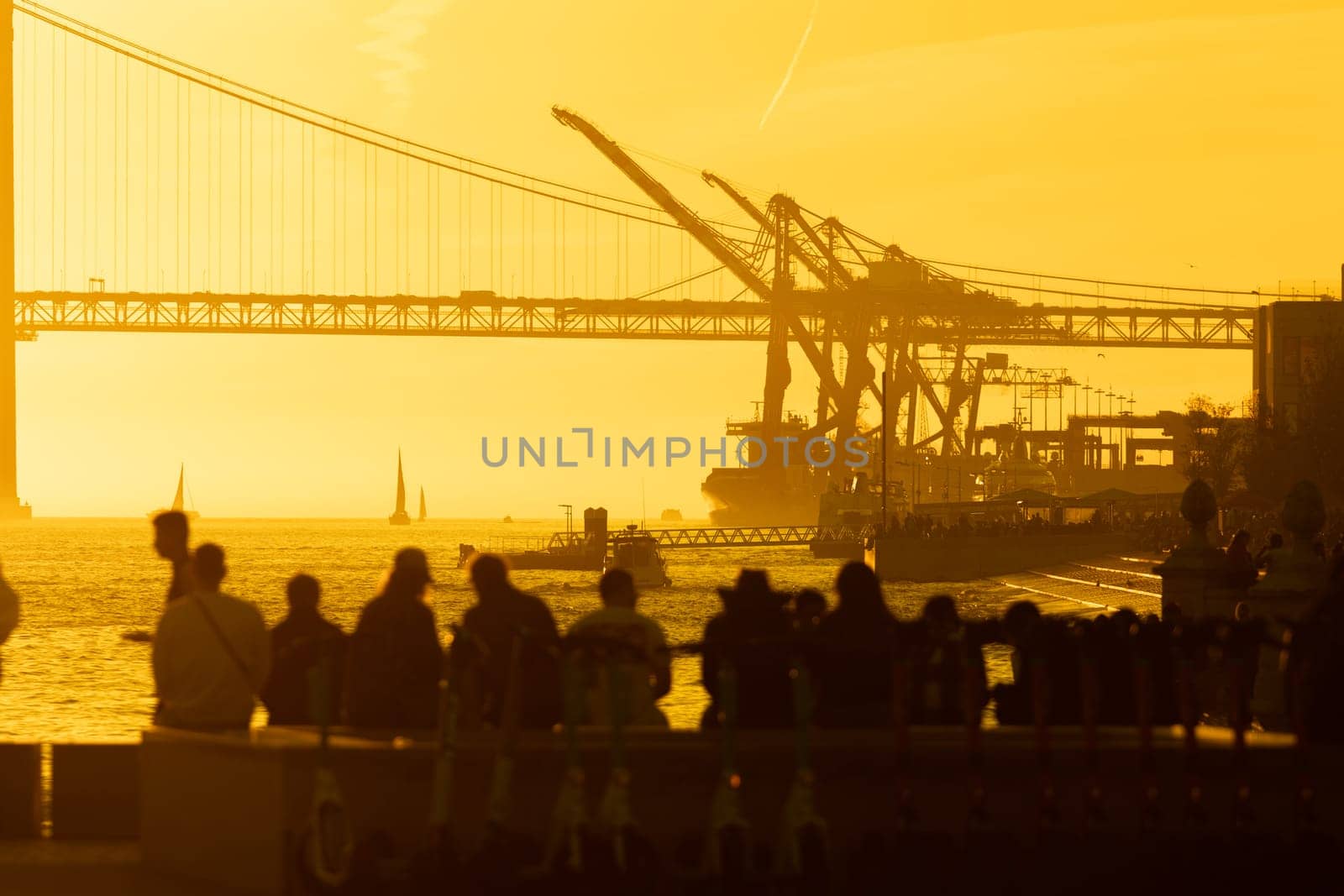 Sunset Silhouette: People Gathering near Bridge as Waves Crash by Studia72
