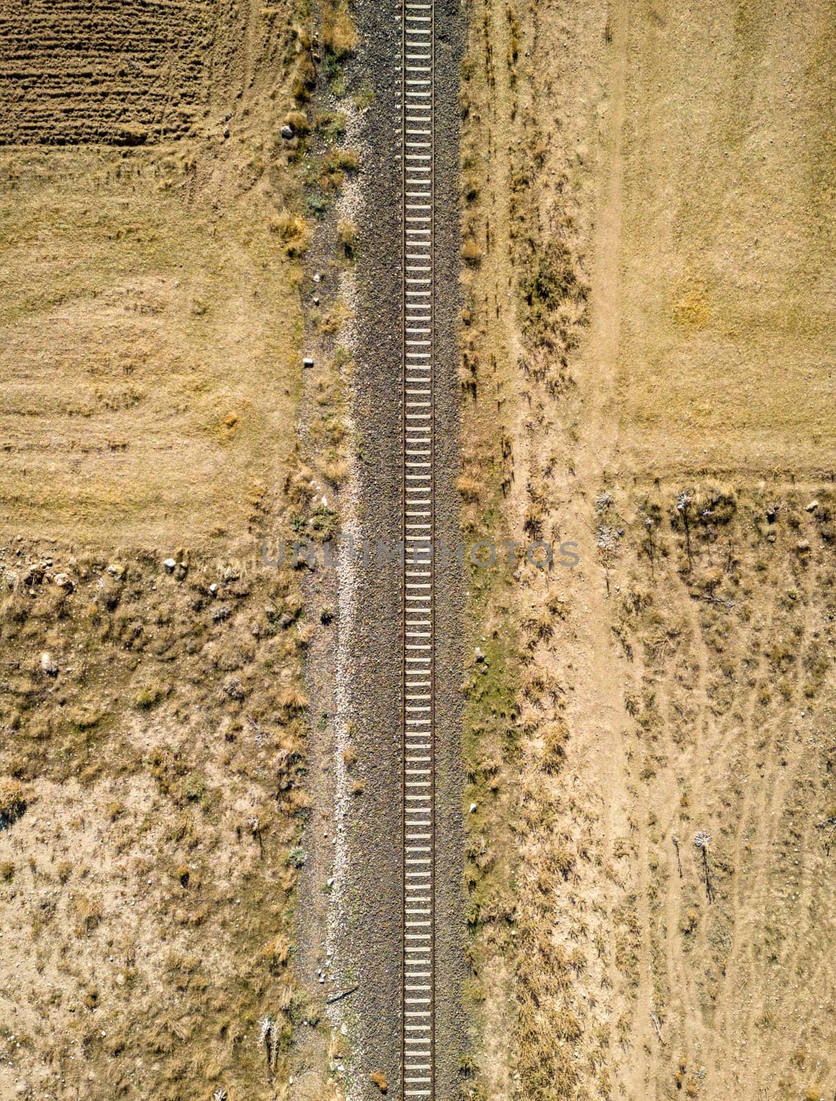 Top view of the train track passing through the arid land, taken with a drone by Sonat