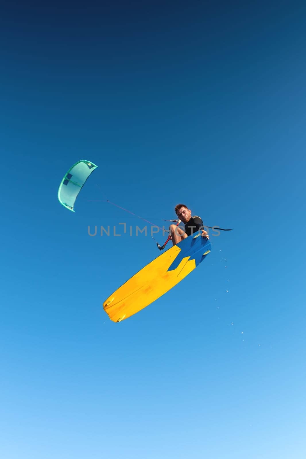 Kitesurfing, professional rider flying performing a trick, looking at the camera while hovering in the air by yanik88