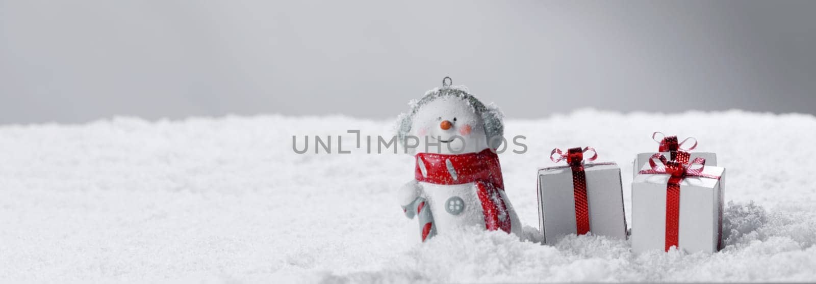 Merry christmas and happy new year greeting card . Happy snowman standing with christmas gifts on gray background