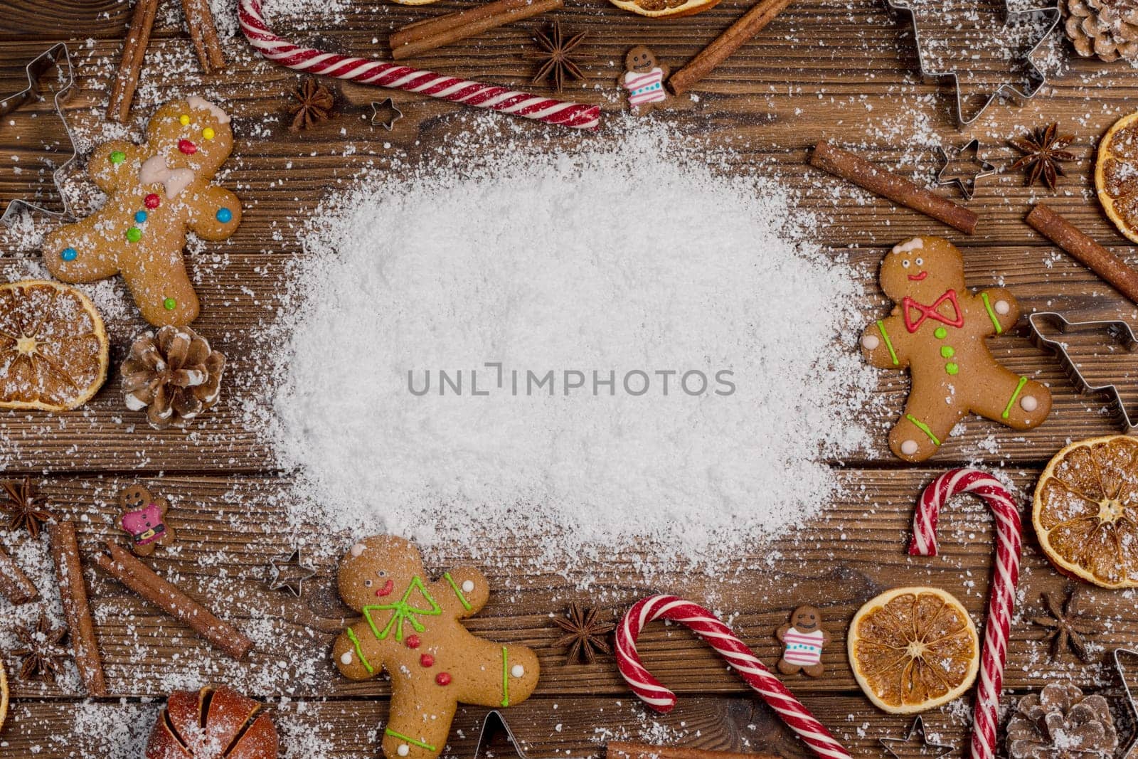 Christmas food frame. Gingerbread cookies, spices and decorations on wooden background with white copy space on snow