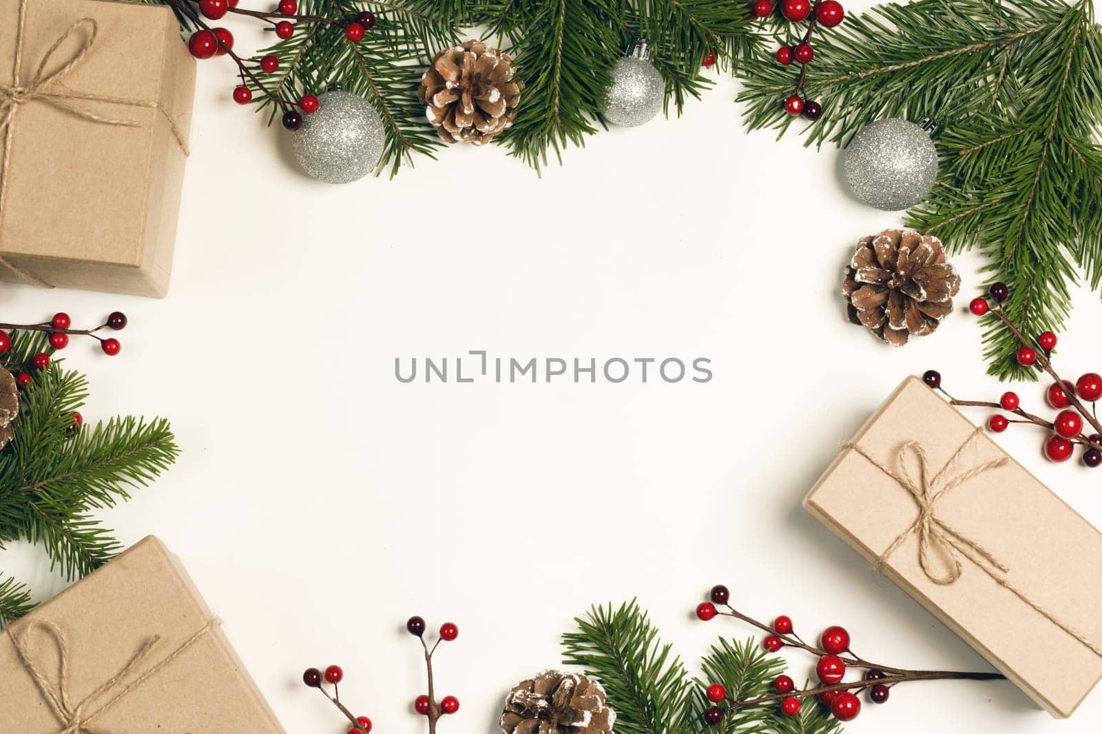 Christmas tree branch with snow , pine cones, red berries and gift boxes on white background with copy space