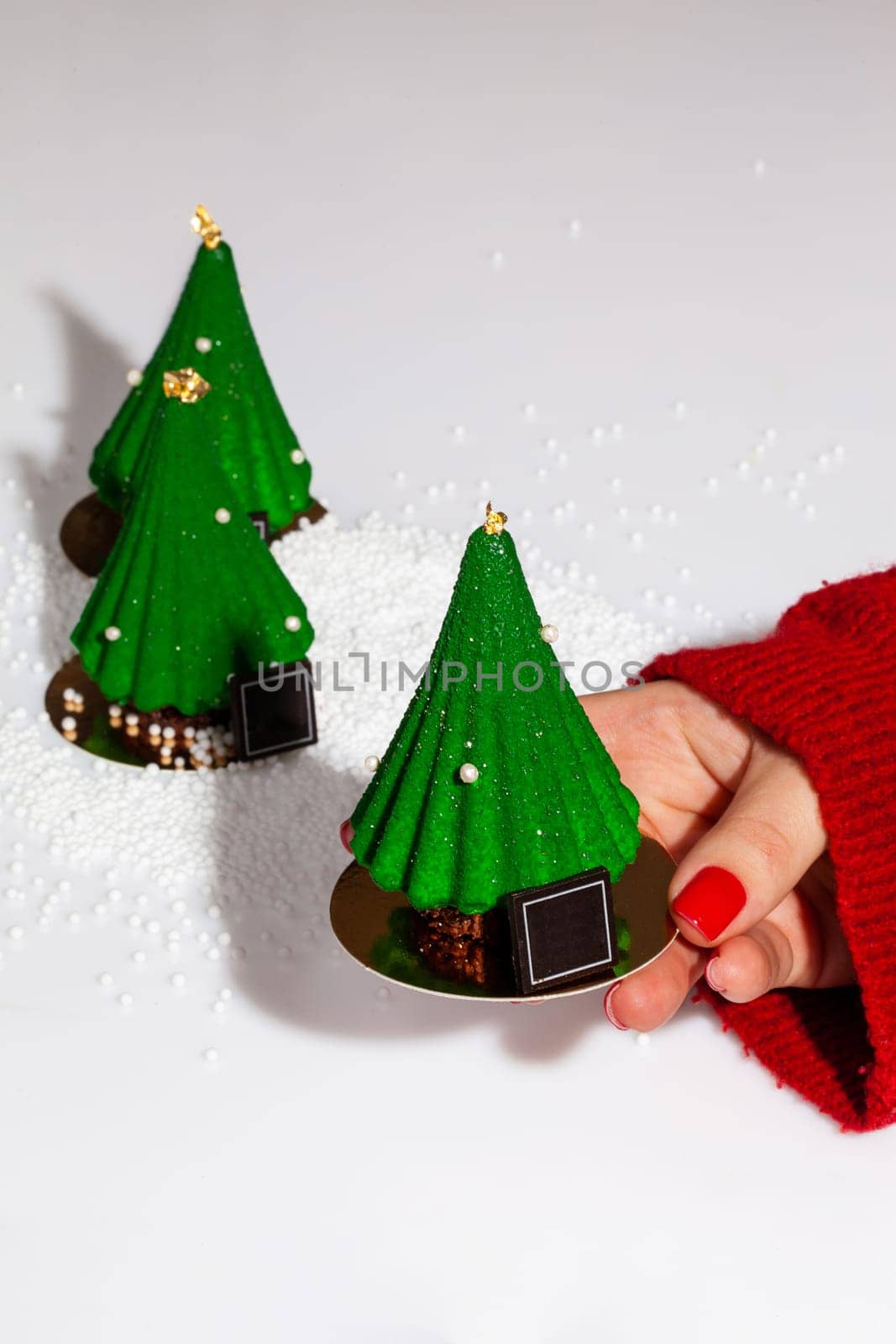 Female hand offering green Christmas tree shaped cake by nazarovsergey
