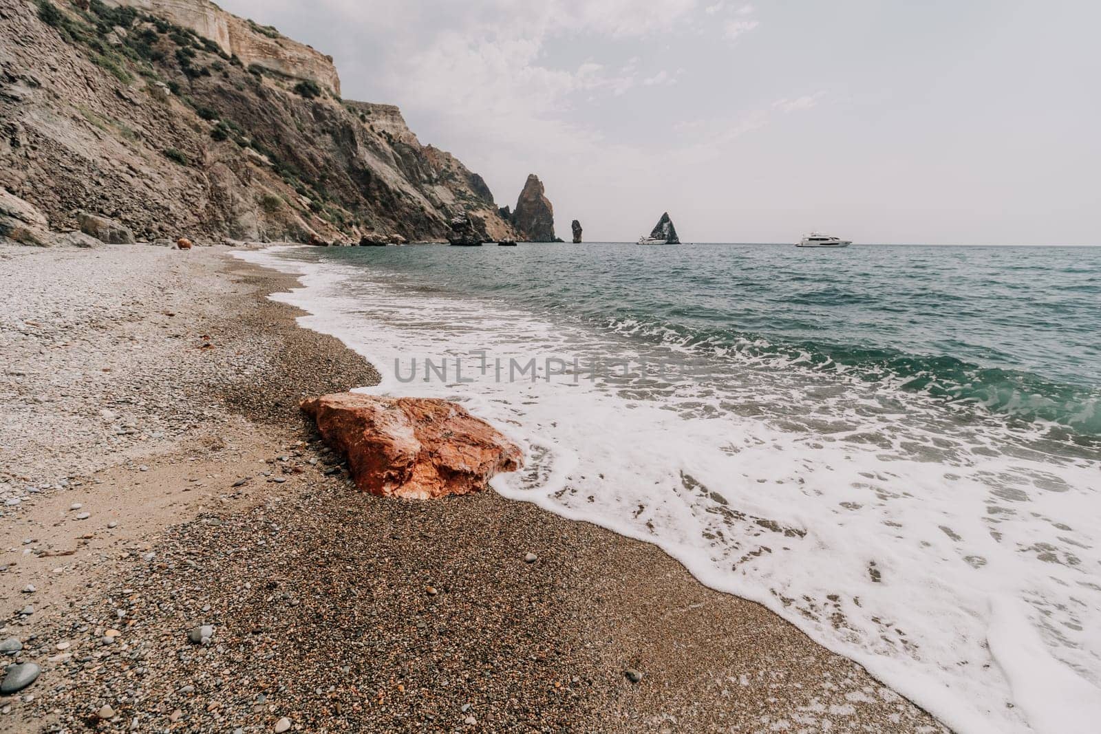 Large red jasper rock on the beach, with the sea in the background. Big Red Jasper Stone Close Up by panophotograph