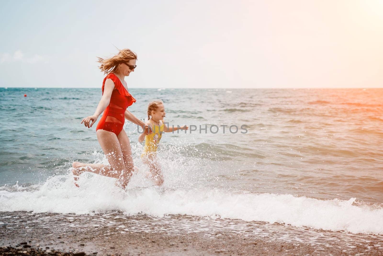 Happy loving family mother and daughter having fun together on the beach. Mum playing with her kid in holiday vacation next to the ocean - Family lifestyle and love concept.