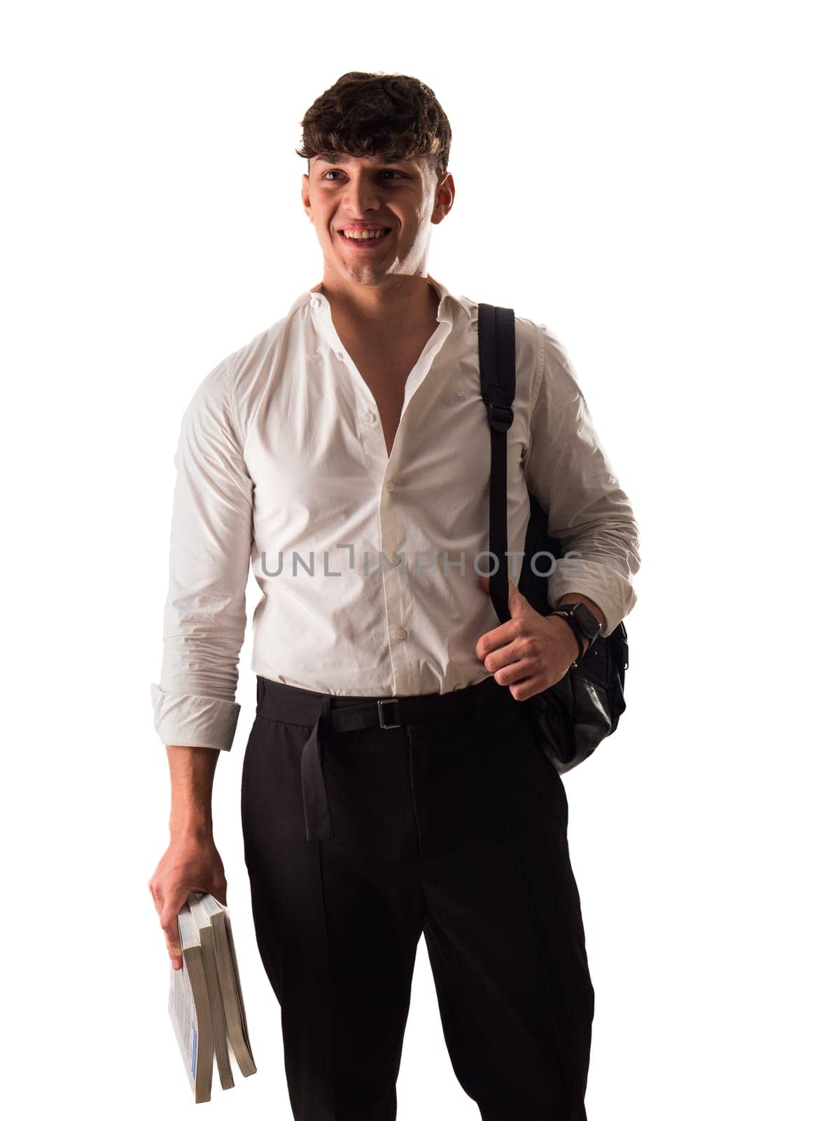 A young attractive man in a white shirt and black pants, a smiling student with backpack and books in one hand