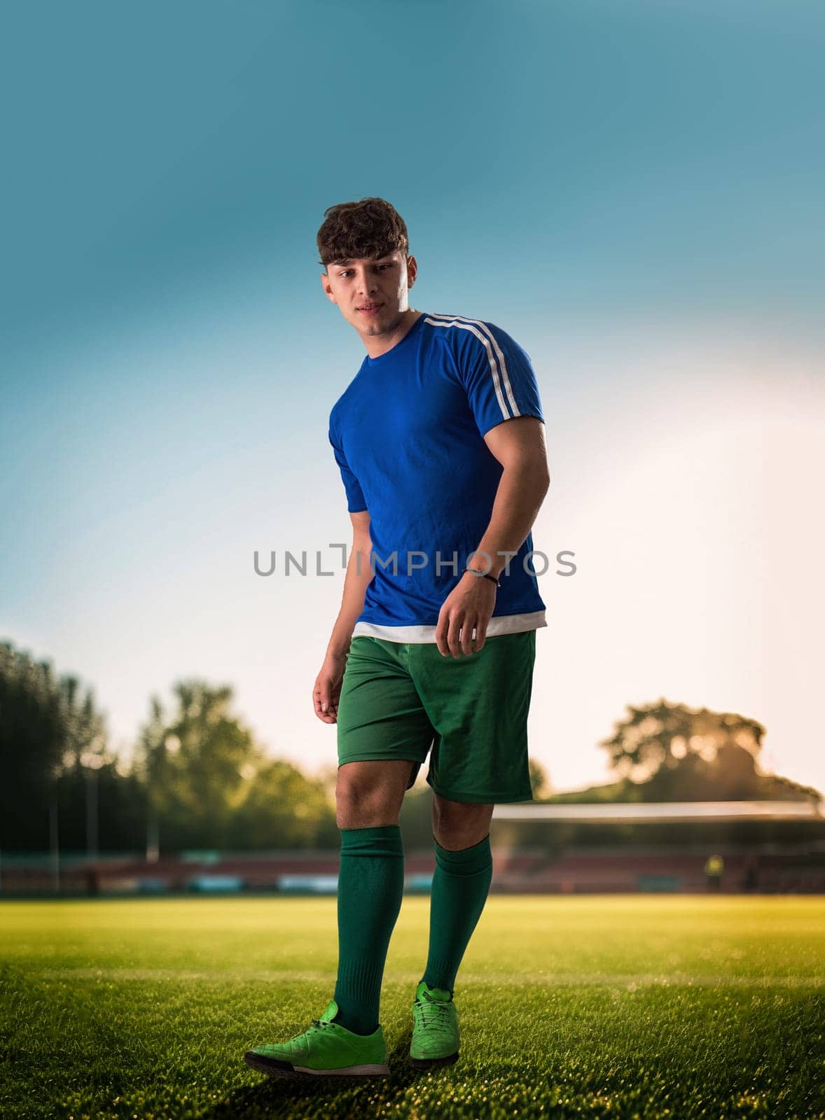 A man in a blue shirt and green shorts standing on a soccer field