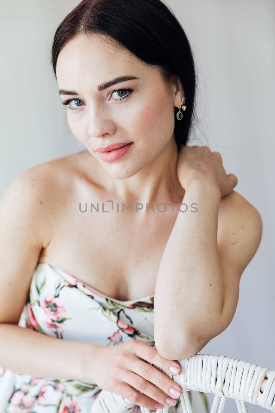 portrait of beautiful brunette woman in a dress by a wicker chair