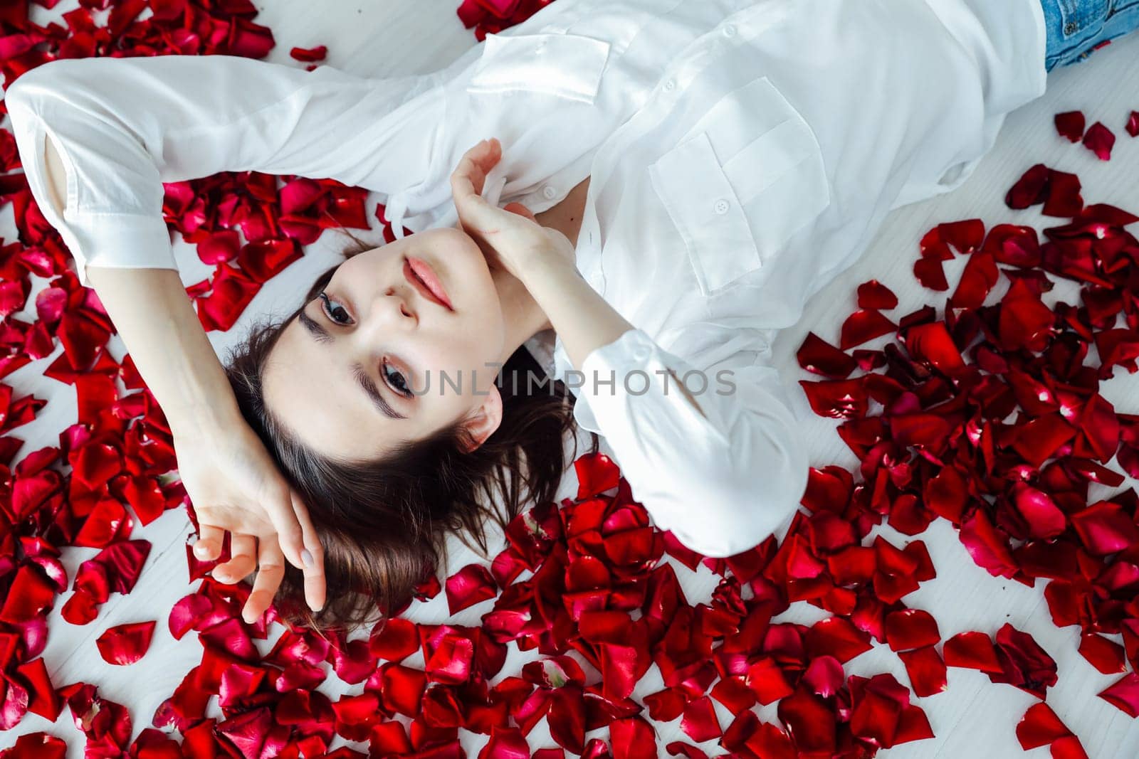 a woman lies in red rose petals romance holiday