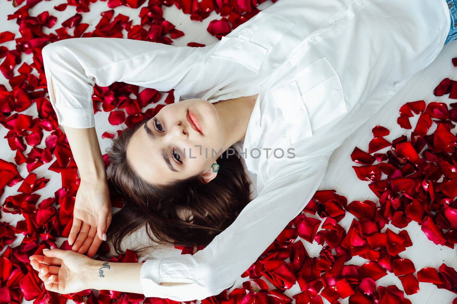 woman lies in red rose petals romance holiday by Simakov