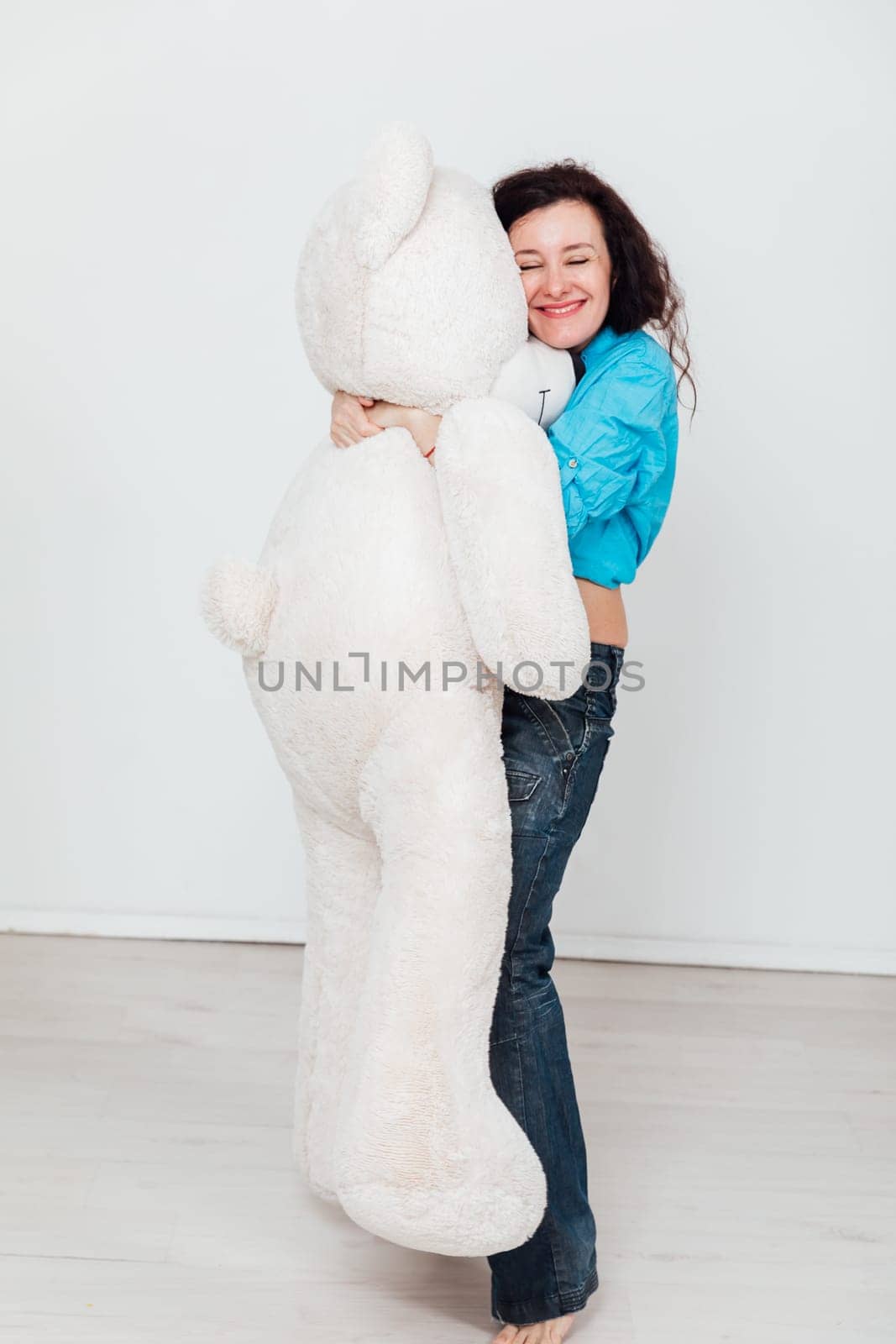 a woman stands with a large soft teddy bear toy by Simakov
