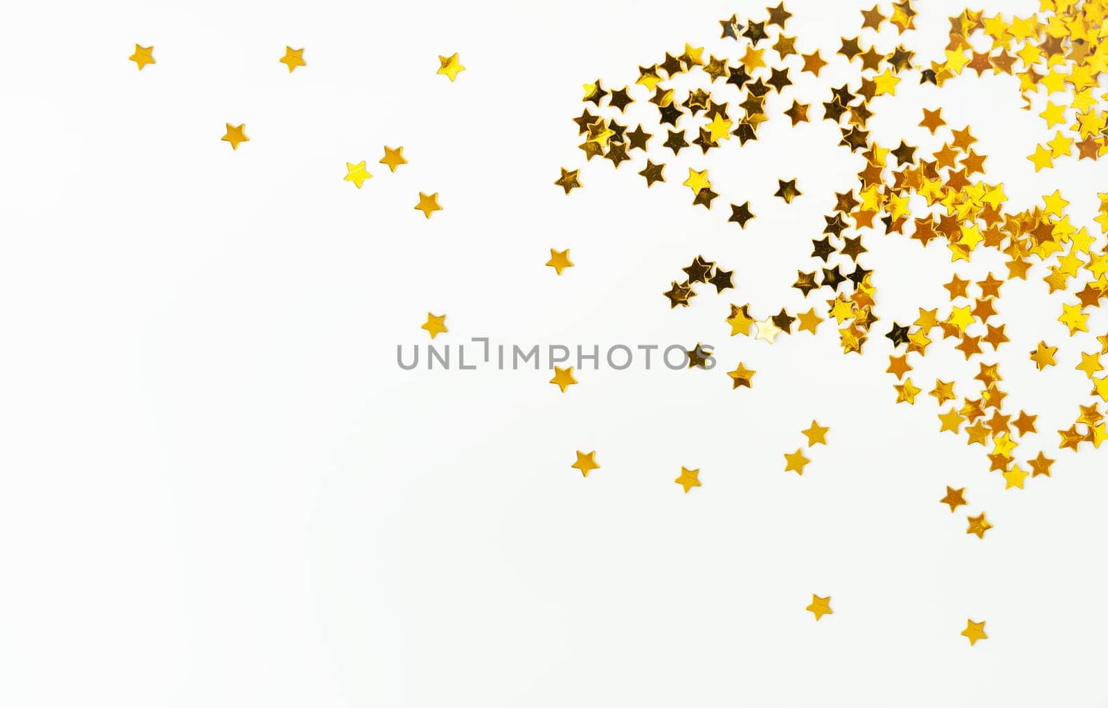 Candies with a golden little star scattered on a white background, concentrated on the right side, there is a place for an inscription. by sfinks