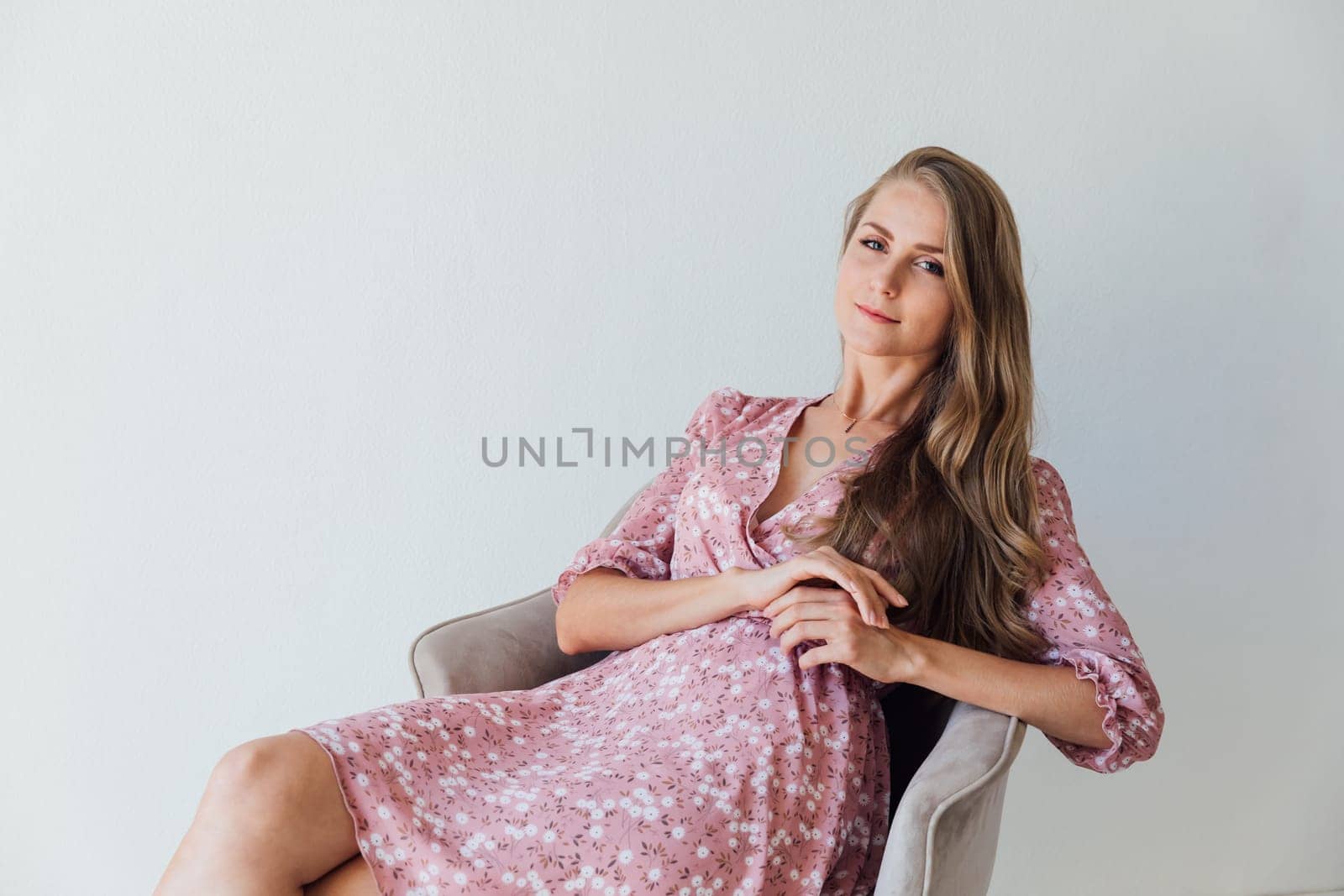 a beautiful blonde in a pink dress sits in a chair in the room by Simakov